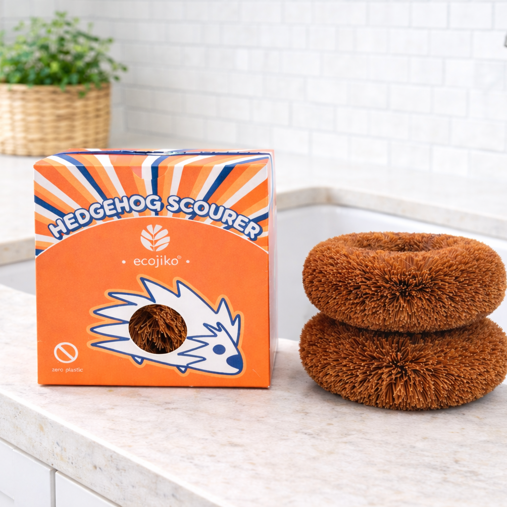 Stack of brown natural coconut scourers next to their packaging on a kitchen counter.
