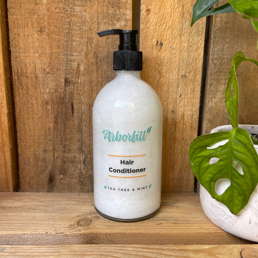 Hair conditioner bottle on a wooden surface with plants in the background